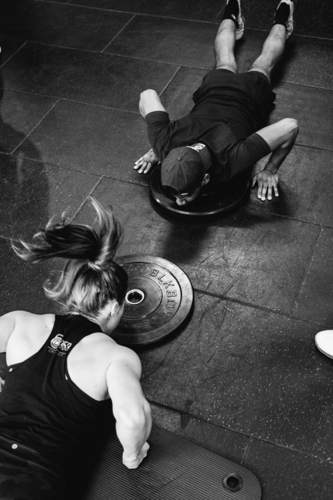 Man and Woman in the same team are doing Push ups during a Crossfit competition. Overhead Image. Black and white image