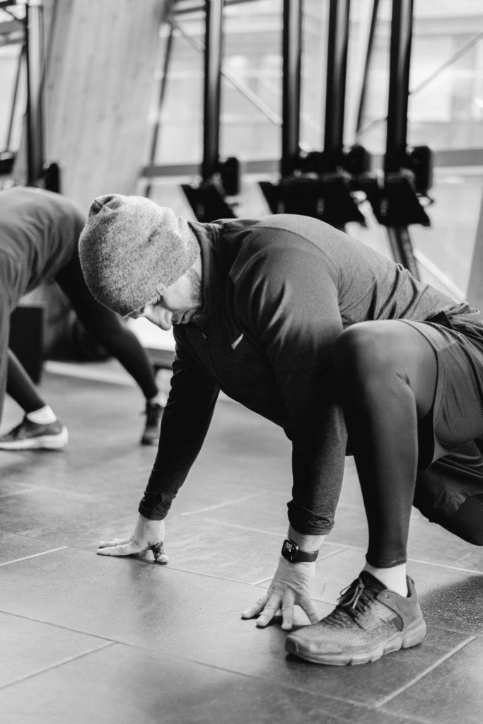 A middle eastern man is warming up at the gym doing stretching.