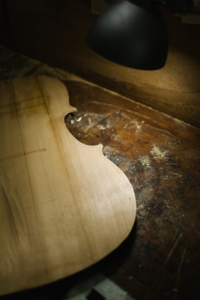 A wooden board is Outlined as a Violin. Violinmaker Workshop detail with Lamp Spotlight