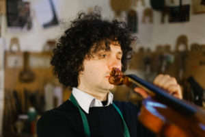 Portrait of a Violinmaker at work checking the Musical instrument