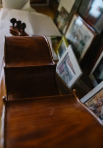 Details of a Violin sit on the Desk with blurred Framed Pictures of people in the background