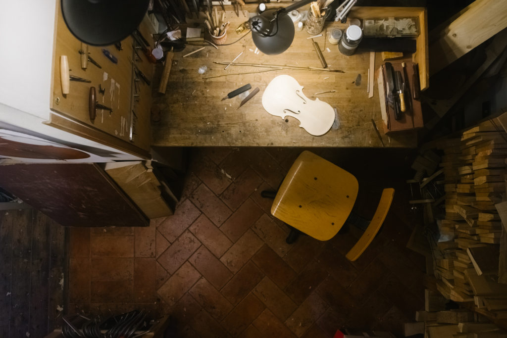 A wooden board is Outlined as a Violin. Violinmaker Workshop detail with Lamp Spotlight