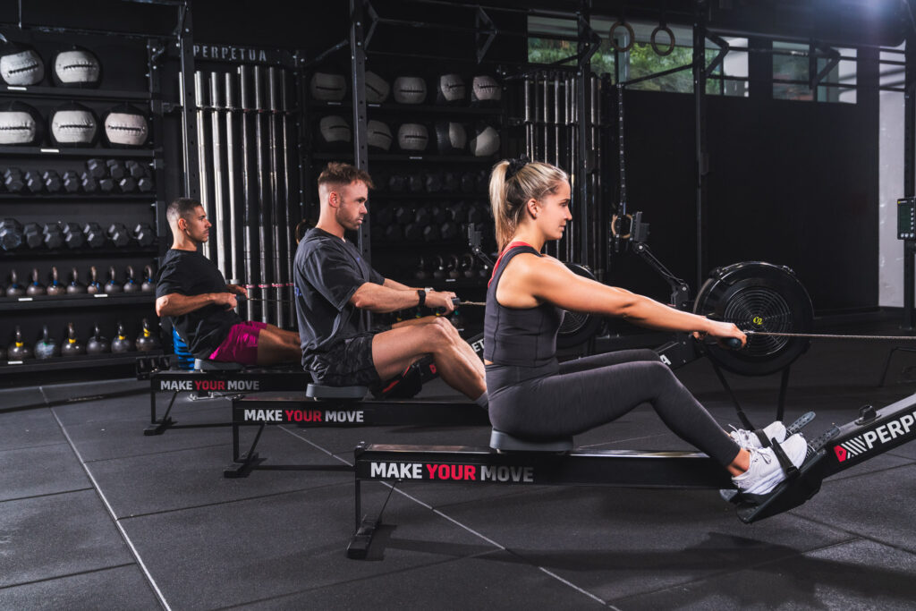 Three people training on rowing machines at Perpetua Gym Dublin, focused on strength and endurance.