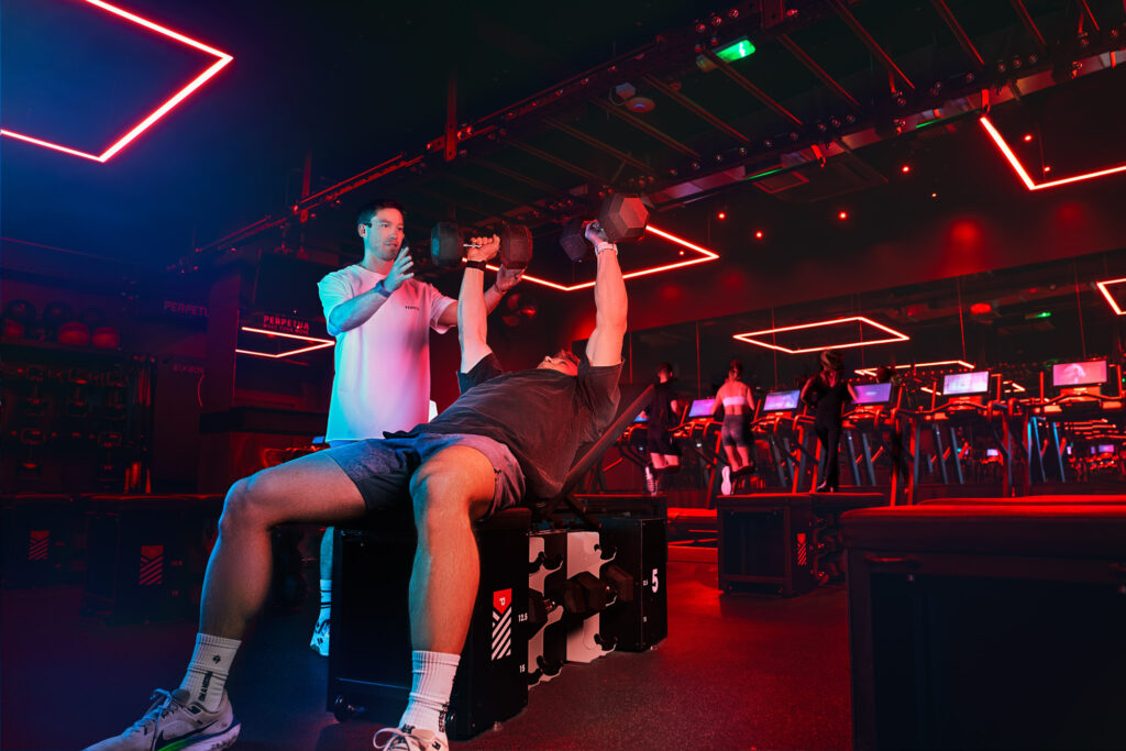 Personal trainer spotting a gym member during a dumbbell bench press at Perpetua Gym Dublin.