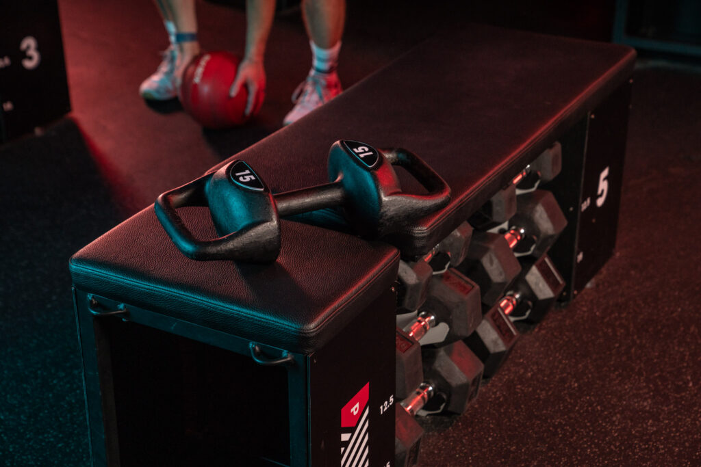 Close-up of gym equipment at Perpetua Dublin, featuring two 15kg kettlebells on a padded bench, with weights and medicine balls in the background. Photo by Mattia Pelizzari Photography, specialising in sport and gym visuals.