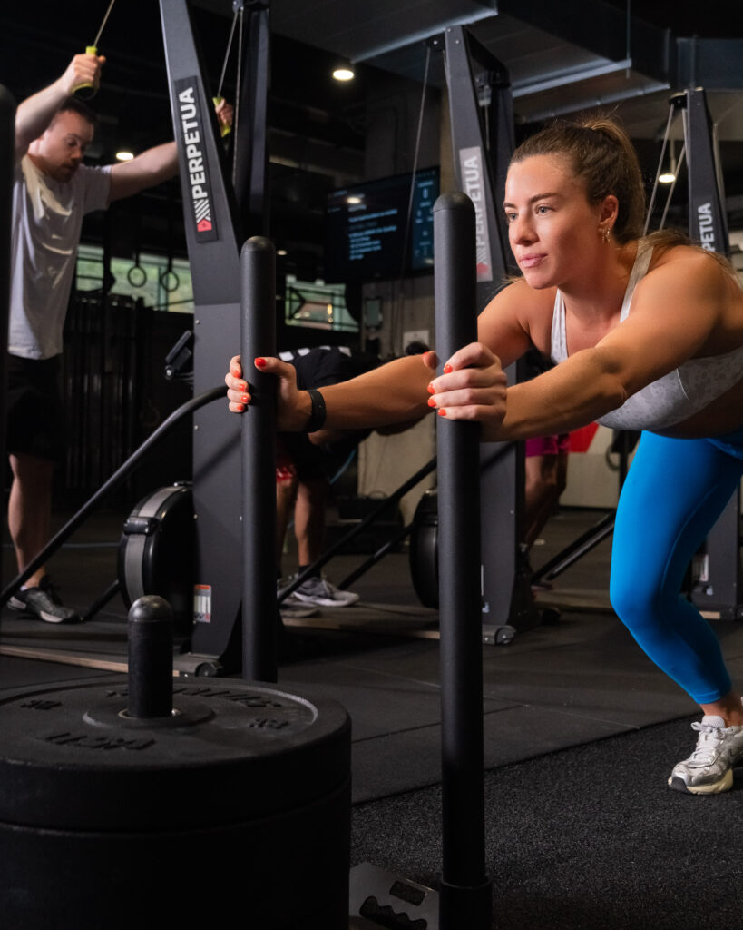 Woman pushing a weighted sled during functional training at Perpetua Gym Dublin.